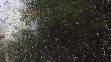 雨滴下降玻璃窗口模糊绿色自然背景